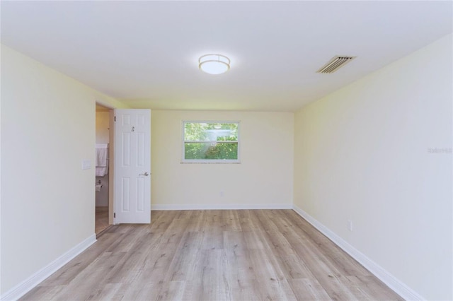 spare room featuring light wood-type flooring, visible vents, and baseboards