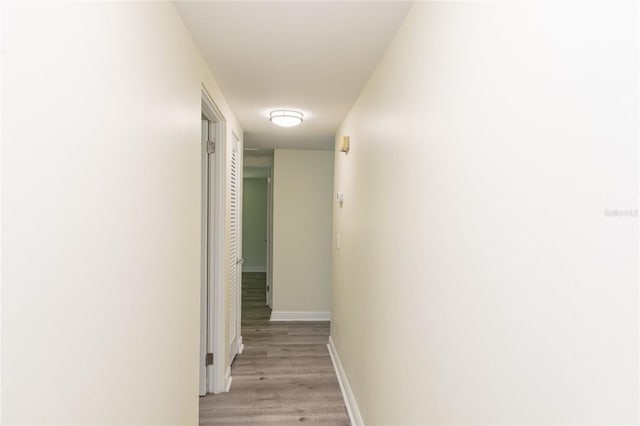 hallway featuring light wood finished floors and baseboards