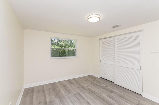 unfurnished bedroom with light wood finished floors, a closet, visible vents, and baseboards