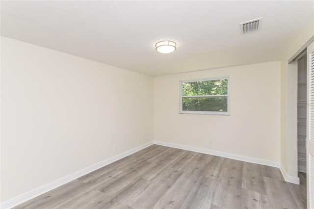 spare room featuring light wood-type flooring, visible vents, and baseboards