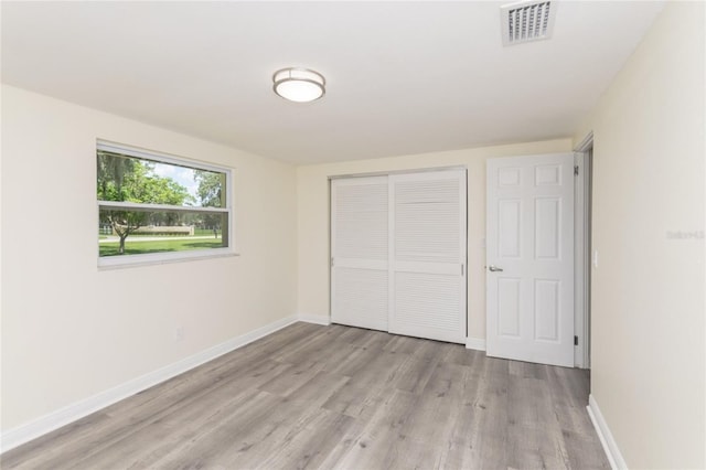 unfurnished bedroom with light wood finished floors, baseboards, visible vents, and a closet