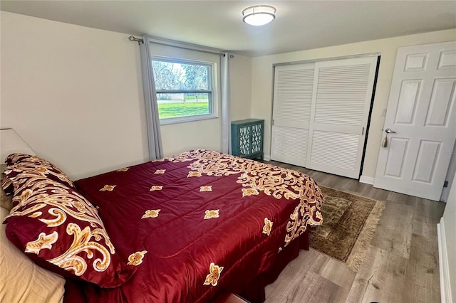 bedroom with a closet, wood finished floors, and baseboards