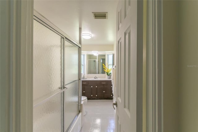 full bathroom featuring toilet, combined bath / shower with glass door, vanity, and visible vents