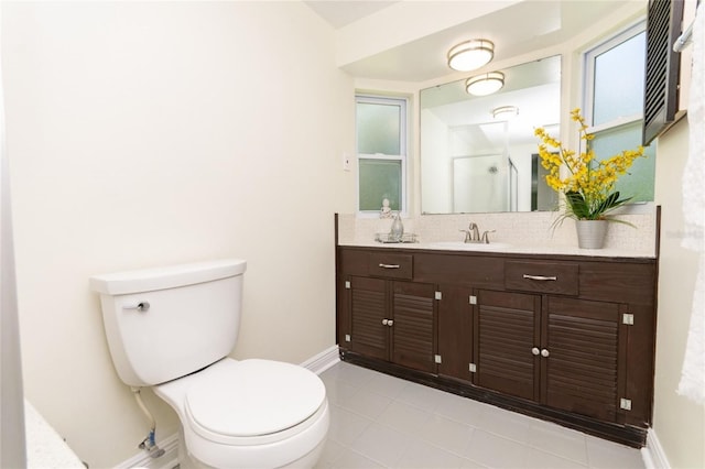 bathroom with toilet, an enclosed shower, baseboards, and vanity