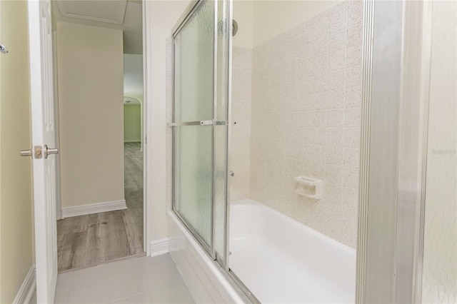 full bath featuring tile patterned flooring, shower / bath combination with glass door, and baseboards