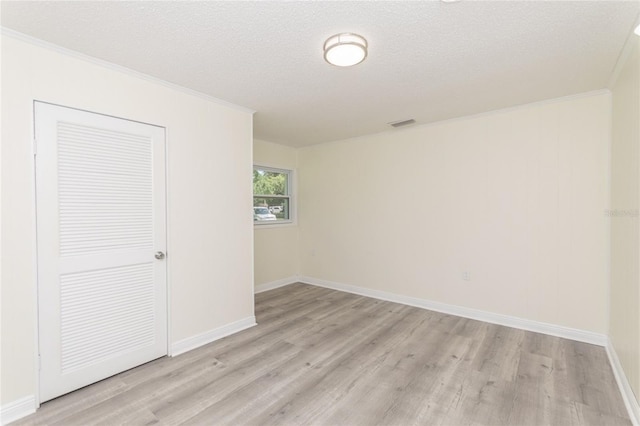 spare room with light wood-type flooring, baseboards, ornamental molding, and a textured ceiling