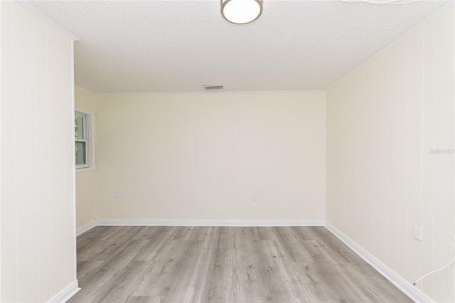 spare room with light wood-style floors, visible vents, baseboards, and a textured ceiling