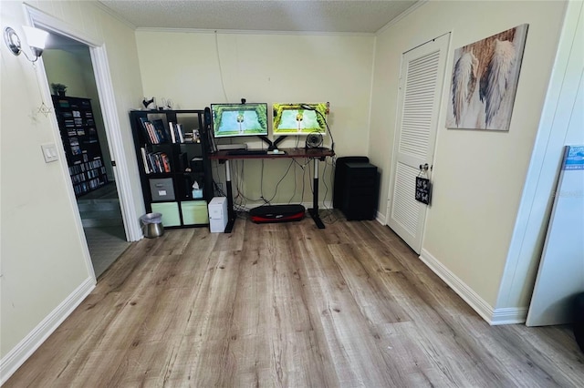 interior space featuring light wood-style floors, ornamental molding, a textured ceiling, and baseboards