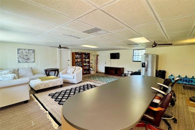 living room featuring ceiling fan, a drop ceiling, and visible vents