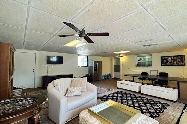 living room featuring a drop ceiling, ceiling fan, and visible vents