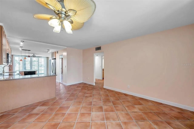 unfurnished living room with a ceiling fan, visible vents, a sink, and light tile patterned floors