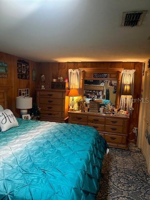 bedroom featuring wood walls and visible vents