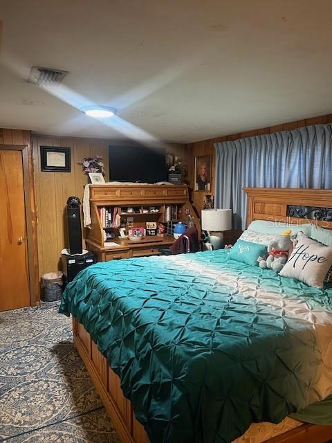 bedroom featuring wooden walls and visible vents