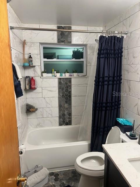 full bathroom featuring tile walls, vanity, toilet, and shower / tub combo with curtain