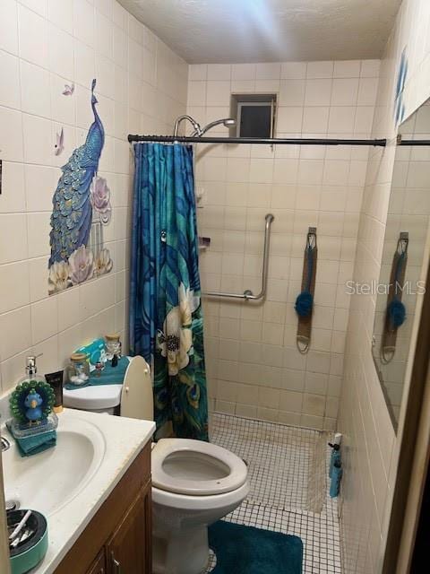 full bathroom featuring toilet, vanity, tile walls, tiled shower, and tile patterned floors