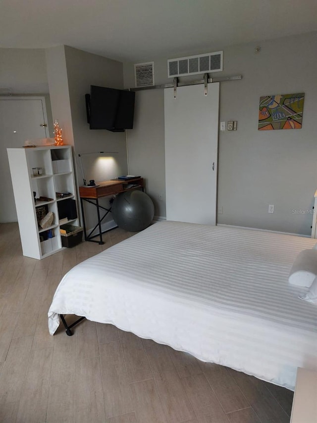 bedroom featuring hardwood / wood-style flooring and a barn door