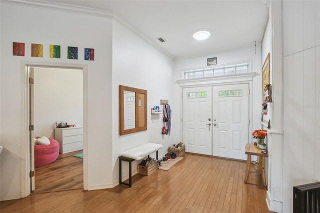 entrance foyer with light wood-style floors, baseboards, visible vents, and crown molding