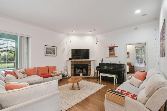 living room featuring a brick fireplace, wood finished floors, and recessed lighting