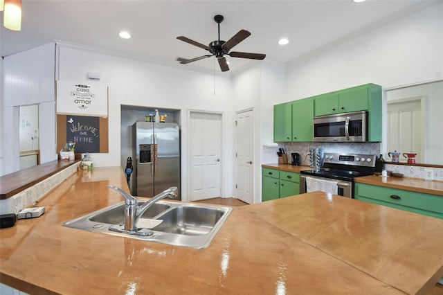 kitchen featuring appliances with stainless steel finishes, a sink, crown molding, green cabinets, and backsplash