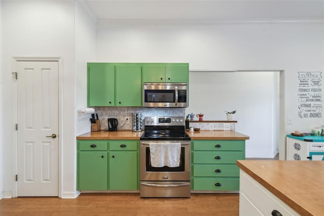 kitchen with light wood-style floors, wood counters, appliances with stainless steel finishes, and backsplash