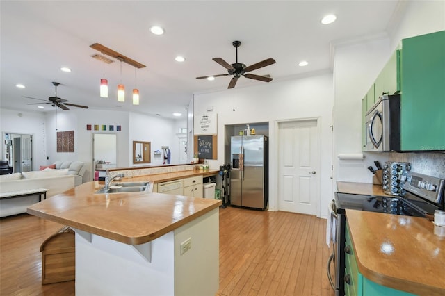 kitchen with recessed lighting, a sink, open floor plan, appliances with stainless steel finishes, and light wood finished floors