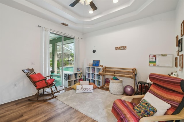 living area featuring baseboards, visible vents, a raised ceiling, wood finished floors, and recessed lighting