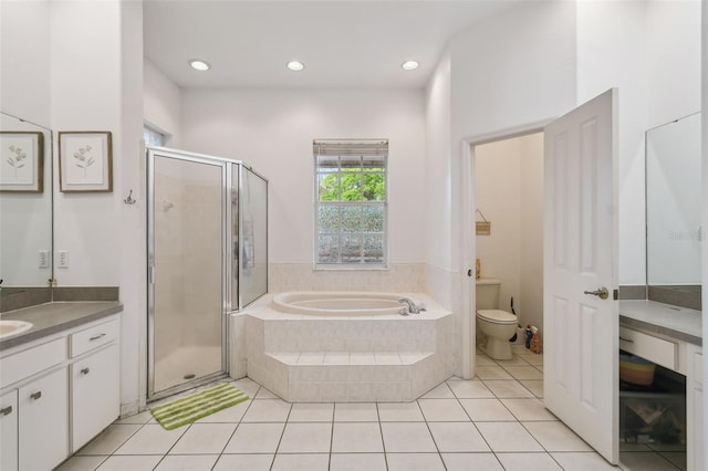 bathroom featuring toilet, vanity, a bath, tile patterned floors, and a stall shower