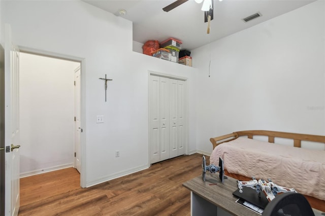 bedroom featuring wood finished floors, a ceiling fan, visible vents, baseboards, and a closet