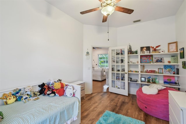 bedroom featuring a ceiling fan, visible vents, and wood finished floors