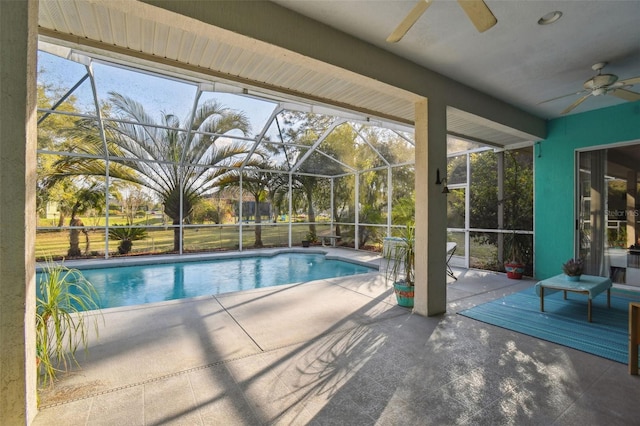 pool featuring a patio area, glass enclosure, and ceiling fan