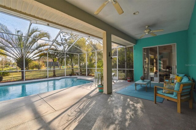 pool with glass enclosure, a ceiling fan, and a patio