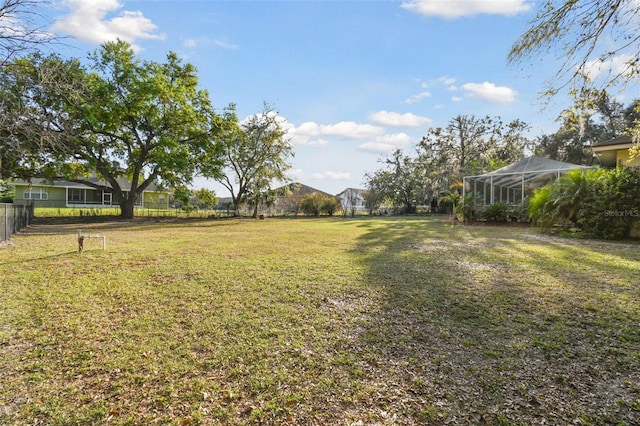 view of yard with glass enclosure and fence