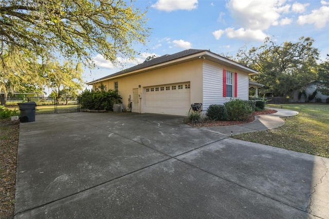 view of home's exterior featuring driveway, an attached garage, fence, and stucco siding