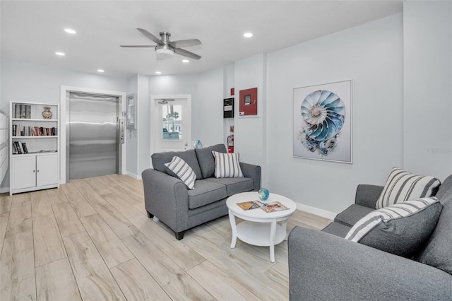 living room featuring ceiling fan, elevator, and light hardwood / wood-style floors