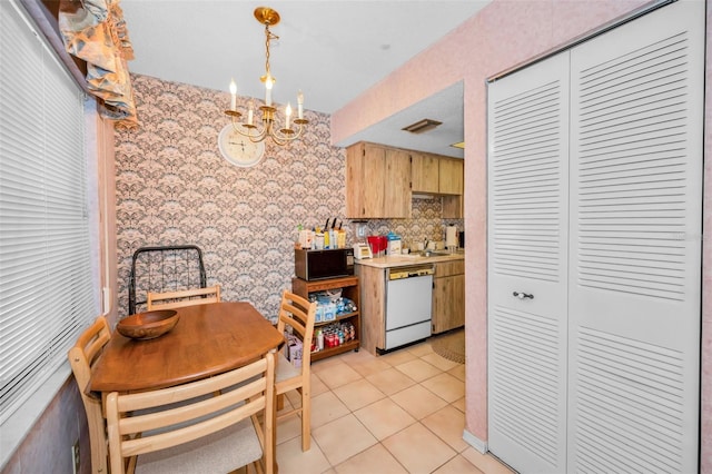 kitchen with light tile patterned flooring, light brown cabinetry, hanging light fixtures, dishwasher, and a notable chandelier