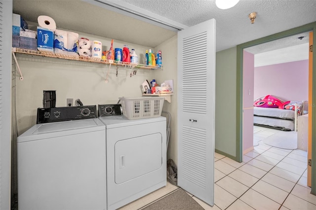 laundry room with light tile patterned flooring, washer and clothes dryer, and a textured ceiling