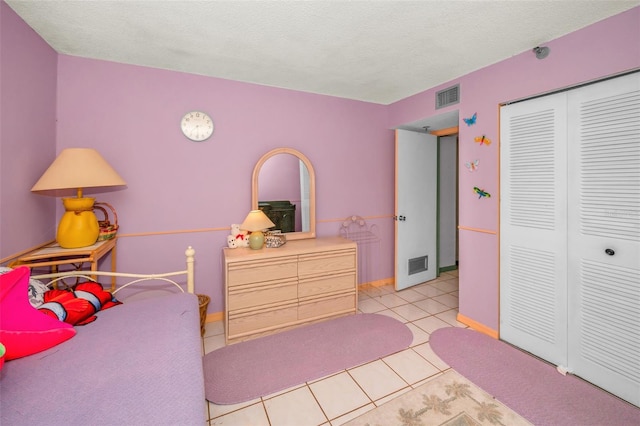 bedroom featuring light tile patterned floors, a closet, and a textured ceiling