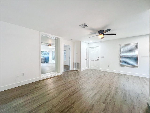 empty room with dark wood-style floors, visible vents, and baseboards