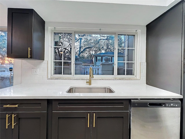 kitchen with a sink, light stone countertops, tasteful backsplash, and dishwasher