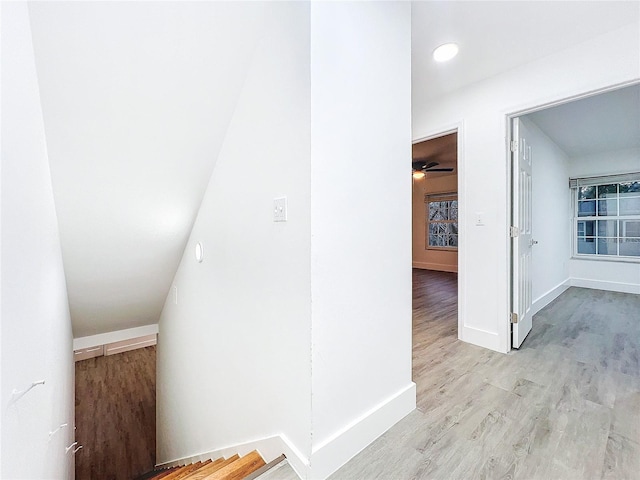 corridor featuring light wood-type flooring and baseboards