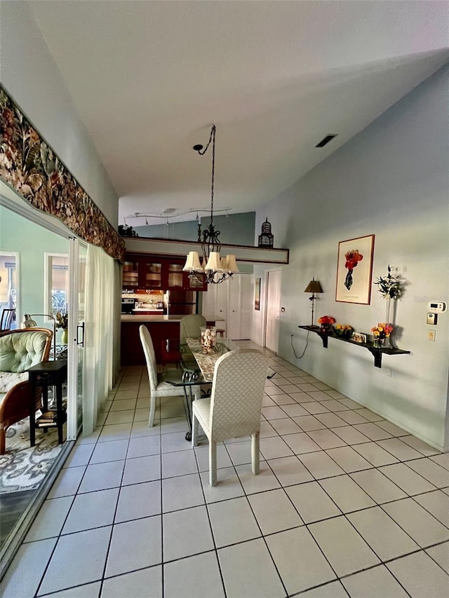 tiled dining room featuring lofted ceiling and a chandelier