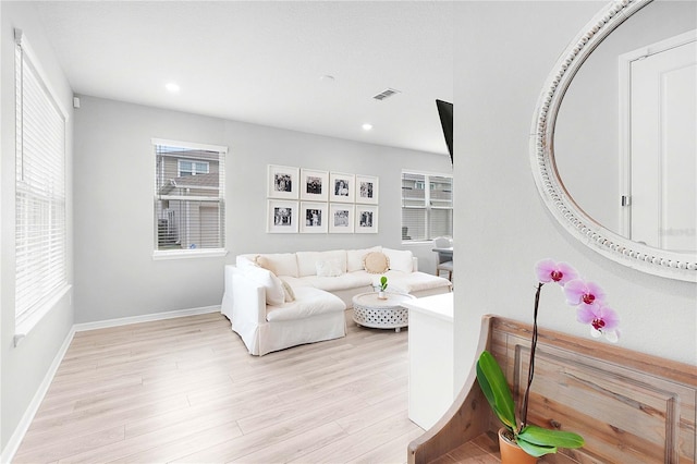 living area featuring light wood-style floors, recessed lighting, visible vents, and baseboards