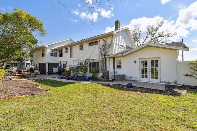 rear view of house featuring french doors, a patio area, a lawn, and fence