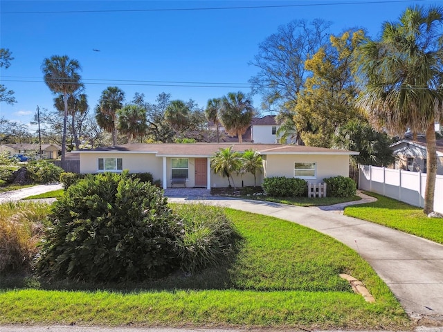 ranch-style house featuring fence, driveway, a front lawn, and stucco siding