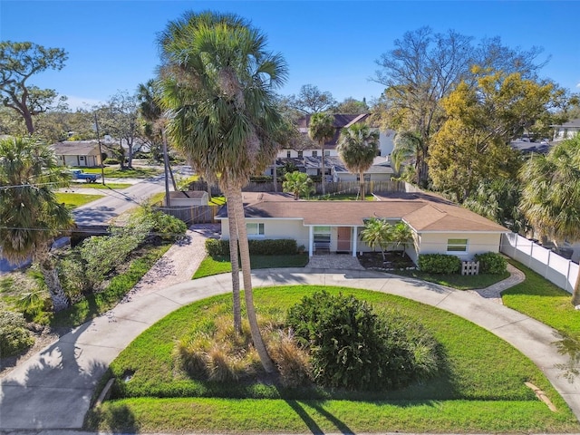 view of home's community with a lawn, a residential view, fence, and concrete driveway