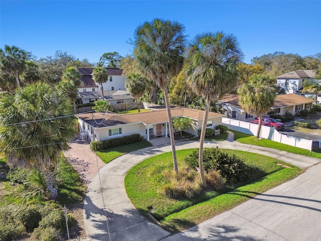 view of front facade with a residential view, curved driveway, and fence