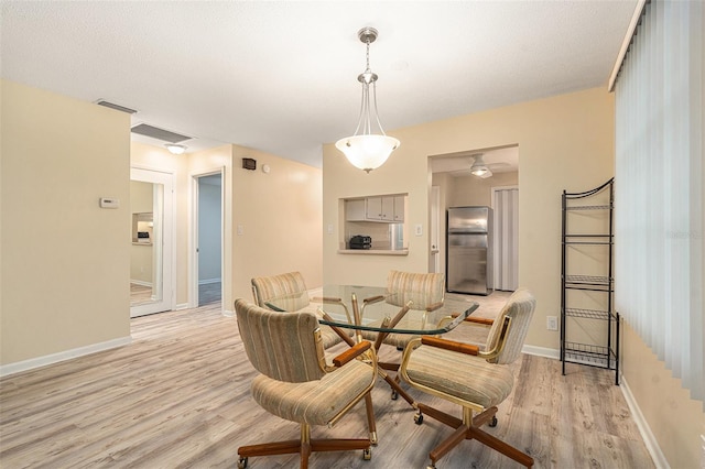 dining space featuring light wood-type flooring, visible vents, and baseboards