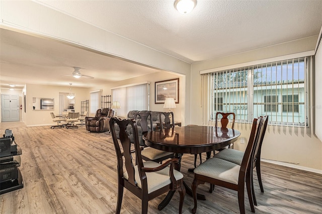 dining area with a textured ceiling, ceiling fan, wood finished floors, and baseboards