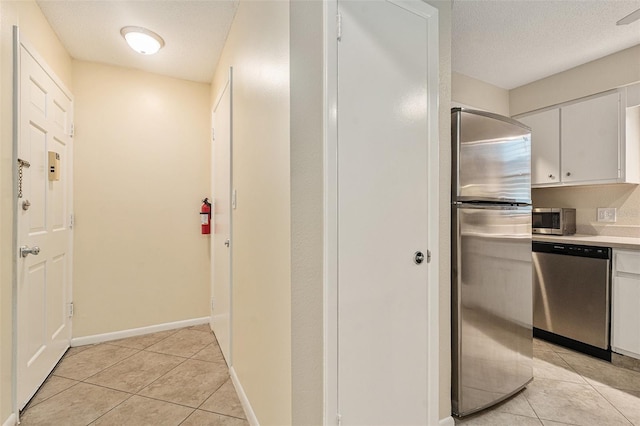 interior space with light tile patterned floors, a textured ceiling, and baseboards