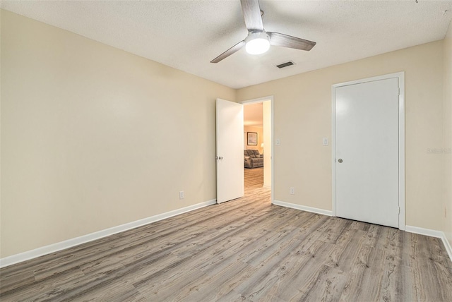 unfurnished bedroom featuring a textured ceiling, light wood finished floors, and baseboards